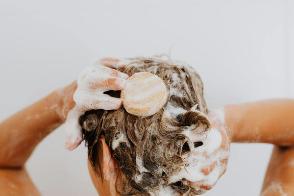 Frau mit natürlichen Locken wäscht ihr Haar mit festem Shampoo – nachhaltige Haarpflege für Afrohaare und Locken